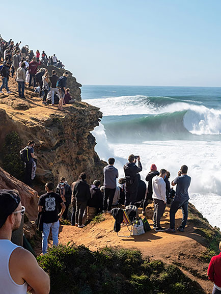 Spectators watching the famous big waves in Nazare, Portugal