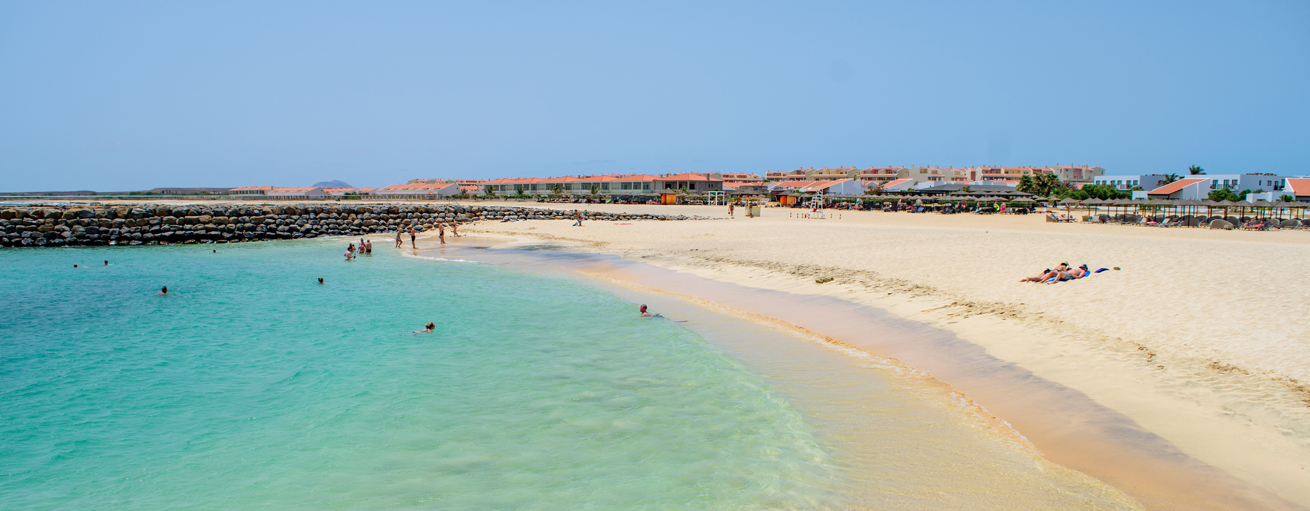 A serene beach in Sal, Cabo Verde, featuring golden sand, calm turquoise waters, and a clear blue sky.